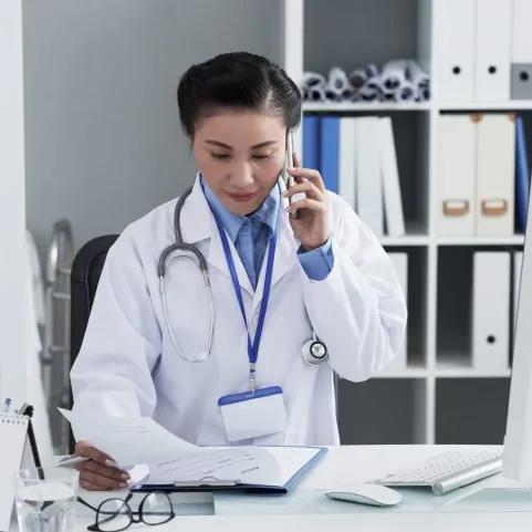 A doctor examining DNA data while speaking on the phone with her patient.